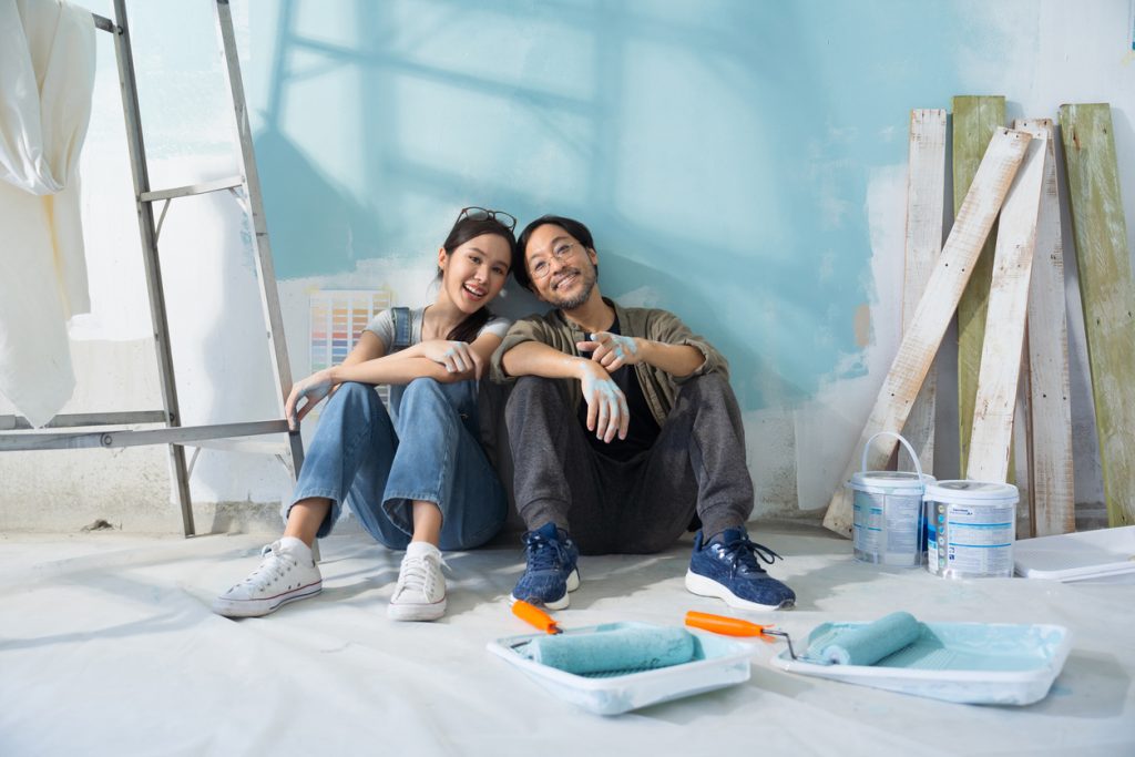 Couple sitting while painting a wall blue.