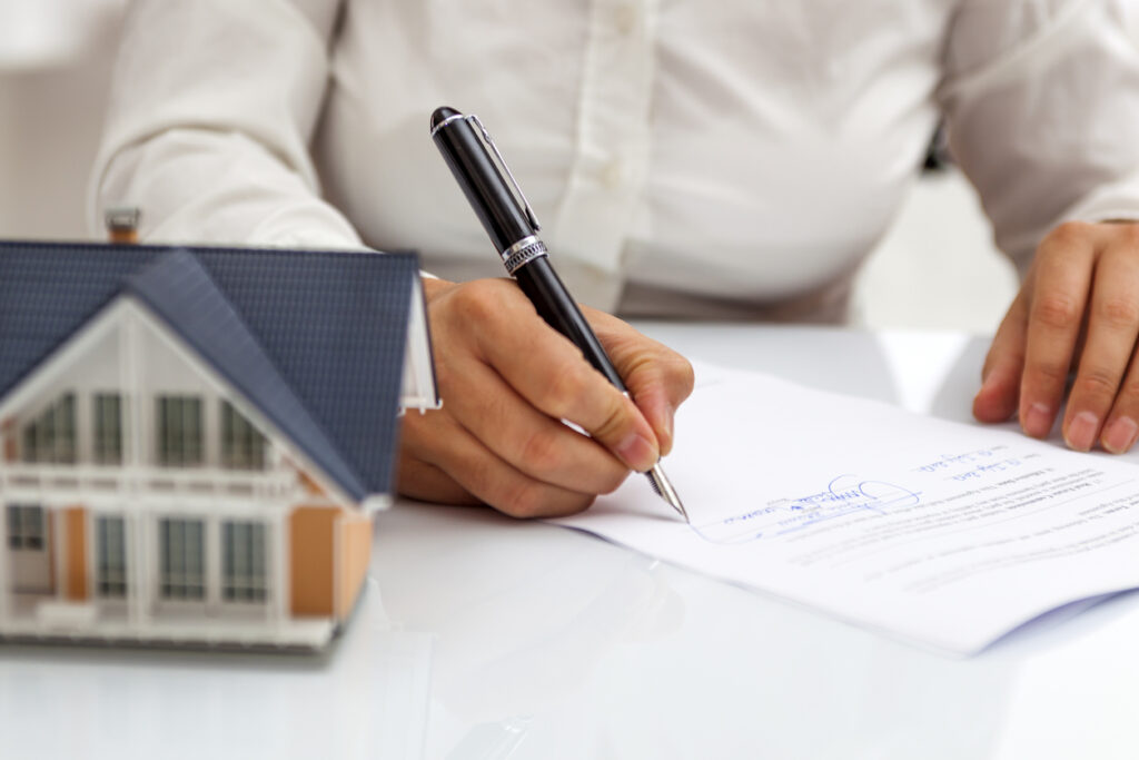 signing arbitration agreement next to a small model of a home