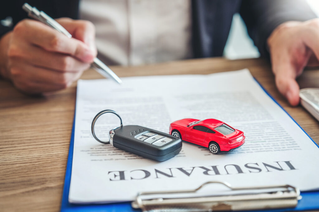 Car keys and toy car on top of insurance contract